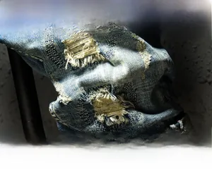Detail of heavy washed blue denim shorts featuring copper zipper and distressed ripped texture