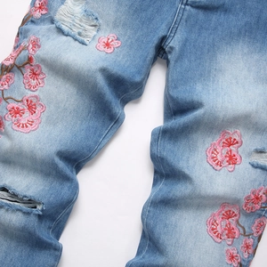 Light blue slim fit flare jeans with distressed rips and pink floral embroidery