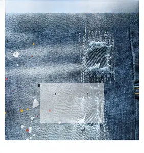 Détail du tissu denim avec taches de peinture et textures de patchwork cousues à la main