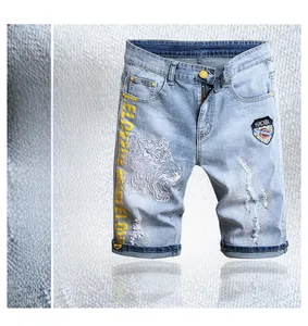 Détail d'un short en jean bleu clair avec broderie tigre et effets de déchirure usés