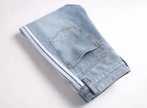 Détail du jean bleu clair avec double bande latérale blanche et texture de denim fin