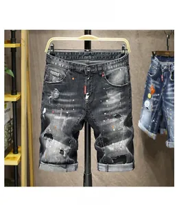 Dettaglio di pantaloncini in denim grigio consumato con schizzi di vernice e risvolto