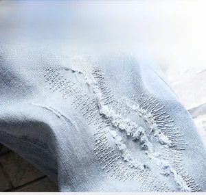 Gros plan détaillé d'un short en jean bleu clair usé avec des patchs cousus à la main