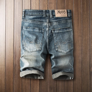 Short en jean vintage pour homme en bleu délavé avec revers sur fond de bois sombre