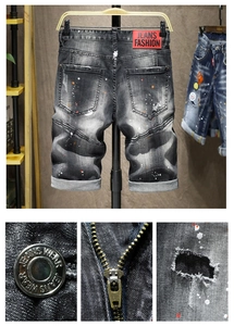 Vista dettagliata dei pantaloncini in denim con schizzi di vernice e toppa in pelle in vita