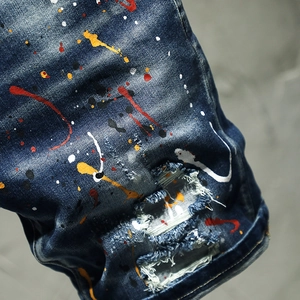 Deep blue denim shorts featuring street style paint splatter and distressed ripped patches