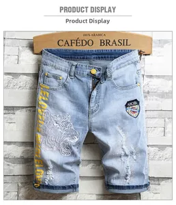 Détail du short en jean bleu clair avec broderie tigre et patchs déchirés tendance