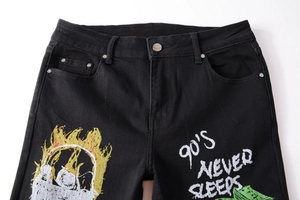 Detail of black slim denim pants with 90's NEVER SLEEPS text and flame graphic print
