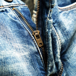 Macro shot of vintage blue denim shorts showing copper zipper with JEANS engraving detail