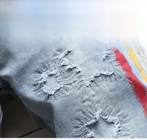 Gros plan sur un short en jean délavé avec détails usés et bandes de peinture colorées
