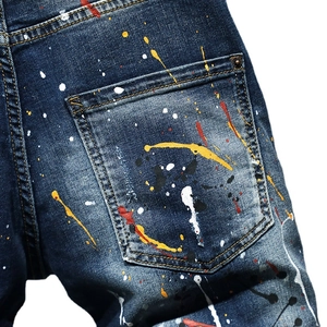 Distressed dark blue denim shorts with colorful paint splatter and back pocket rivets