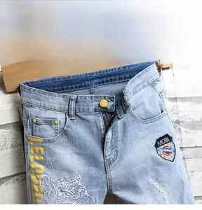 Détail du short en jean bleu clair avec bouton S jaune et broderie tête de tigre