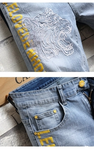 Détail du short en jean bleu clair avec broderie tigre et bouton en métal avec lettre S