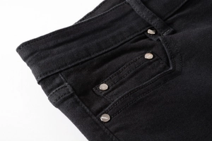 Close-up of black denim jeans waist with silver metal rivets and textured fabric