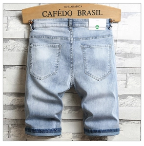Détail d'un short en jean bleu clair avec délavage vintage et écusson logo en cuir au dos