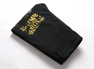Gros plan sur denim noir avec impression métallique AMI dorée et coutures précises