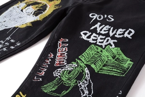Detailed view of the 90's Never Sleeps graffiti and bone hand print on black jeans