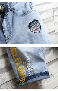 Détails du short en jean bleu clair délavé avec broderie écusson et lettrage jaune vif