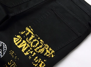 Détail de la poche arrière en denim noir avec imprimés jaune et blanc de style urbain