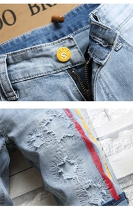 Détail de trous en forme d'étoile et bandes latérales rouge-jaune sur short en jean bleu