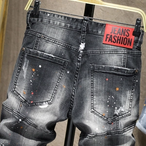 Pantaloncini di jeans neri distressed con schizzi di vernice e toppa in pelle rossa