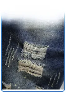 Detail shot of distressed dark blue denim with ripped holes and washed texture