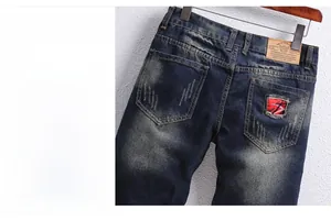 Detailed view of dark blue washed denim shorts featuring distressed holes and red patch