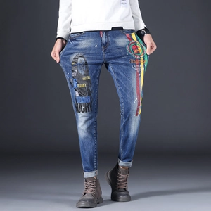 Detail of slim-fit denim jeans featuring colorful embroidery and street art prints