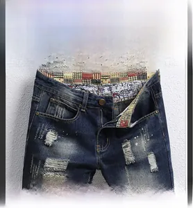 Detail view of denim shorts with ripped patches, distressed finish and red plaid lining