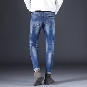 Detailed back view of slim-fit denim jeans with wash effects and white paint splatters