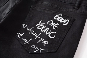 Detail of black denim back pocket featuring white graffiti print and textured fabric