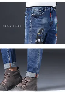 Detail of slim-fit men's blue jeans featuring portrait prints and embroidery details