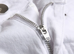Gros plan sur la fermeture éclair en métal et le bouton JEANS sur denim blanc épais
