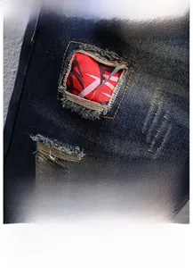 Macro detail of distressed dark blue denim with red geometric pattern patchwork and texture