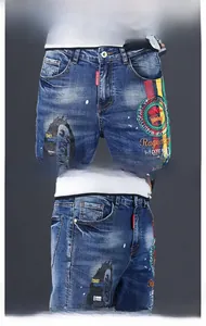 Close-up detail of vintage blue jeans featuring Bob Marley portrait print and paint splatters