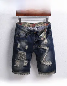 Detail of distressed denim shorts with vintage patterns and washed ripped texture