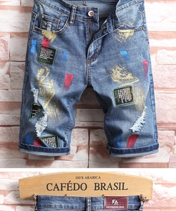 Détails du short en jean bleu délavé avec éclaboussures de peinture et écussons street