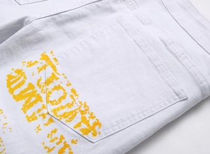 Détail du jean blanc montrant l'imprimé graffiti jaune sur la poche arrière et coutures