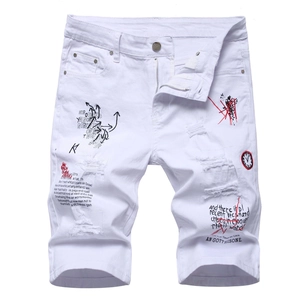 Close-up of white slim denim shorts featuring distressed holes and graffiti embroidery