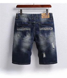Detail view of denim shorts showing distressed rip design and vintage wash texture on the back