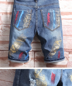 Gros plan détaillé du short en jean pour homme avec éclaboussures de peinture et déchirures