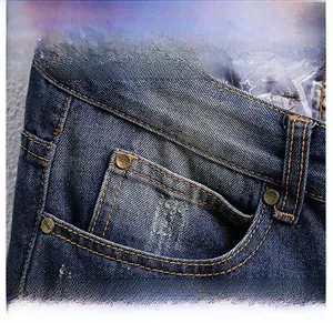 Close-up of front pocket details on distressed blue denim shorts with copper rivets