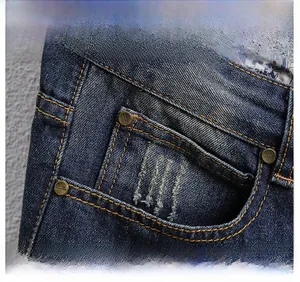 Detail of distressed dark blue denim shorts with yellow stitching and floral fabric lining