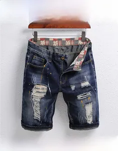 Nahaufnahme der Distressed-Denim-Shorts mit starken Rissen und bunten Farbspritzern