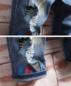 Détails de short en jean bleu montrant des déchirures et des imprimés graffiti colorés