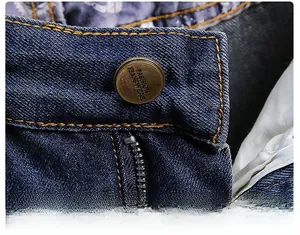 Macro shot of denim waist details with retro copper button and classic orange stitching