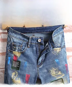 Détail d'un short en jean usé avec des éclaboussures de peinture et des patchs brodés