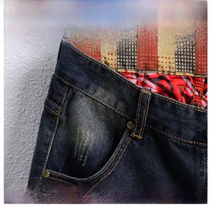 Detailed close-up of dark blue denim front pocket with copper rivets and red patterned lining