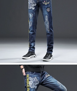 Détail de la broderie tête de tigre et des écussons sur le jean bleu extensible pour homme