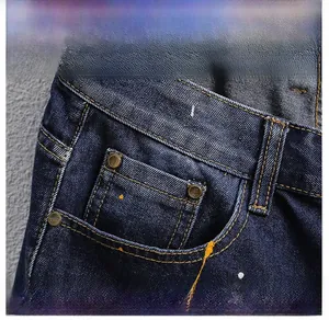 Detail der dunkelblauen Denim-Shorts mit gelben Farbspritzern und Metallnieten-Tasche